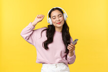 People Emotions, Lifestyle Leisure And Beauty Concept. Carefree Good-looking Asian Woman Close Eyes And Dancing Relaxed With Smartphone, Listening Music In Wireless Headphones