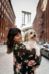 Wall Mural - a woman posing with her small mixed breed dog in front of manhattan bridge at dumbo, brooklyn