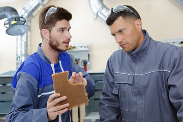 young male worker showing mesh product to his supervisor