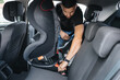 © Aleksandr - Man installs a child car seat in car at the back seat. Responsible father thought about the safety of his child. Man fasten seat belt on baby car seat