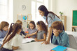 © Studio Romantic - Group of children looking at picture that little girl is showing. Happy school teacher and students have interesting classes, learn, discuss new things, work on creative projects in modern classroom