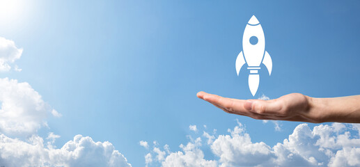 Male hand holding rocket icon that takes off, launch on blue background. rocket is launching and flying out, Business start up, Icon marketing on modern virtual interface.Start up concept.