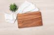 Wood cutting board with white linen napkin and plant pot