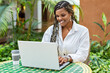 © Juan Algar - African American woman using laptop in a cafe store outside