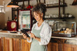 © (JLco) Julia Amaral - Happy cafe owner running her business on a digital tablet