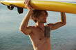 © Drobot Dean - Young european surfer carrying surfboard on head