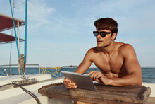 Young Man Using Digital Tablet Of His Yacht In Sea