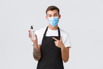 Wall Mural - Coronavirus, social distancing in cafes and restaurants, business during pandemic concept. Waiter or barista explain importance of wearing mask and using hand sanitizer to disinfect