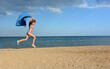 Teen girl jumping with scarf over sandy beach
