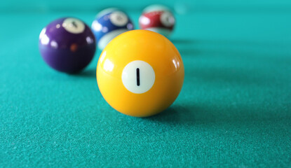 Balls from a pool or billiard on a billiard table with a number 1 ball on green background.