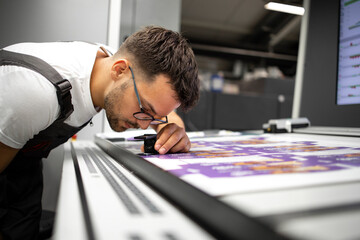 Wall Mural - Worker checking print quality of graphics in modern printing house.