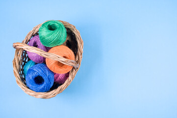 Canvas Print - Closeup shot of colored cotton threads in a basket on a blue background