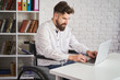 © yuriygolub - Chief sitting in a wheelchair and working on a laptop