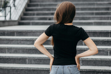 Wall Mural - Stylish brunette girl wearing black t-shirt and glasses posing against street , urban clothing style. Street photography