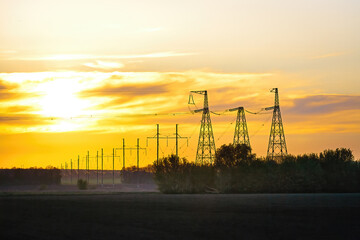 Wall Mural - Transmission tower at sunset. Electric transmission station with metal poles and electrical wires.