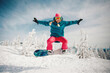 pretty young woman on the snowboard jumping on the slope in winter