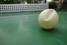 Closeup Shot Of A Squashed Ping Pong Ball On The Green Table Outdoors