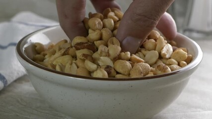 Sticker - Fingers taking peanuts out of a bowl in super slow motion