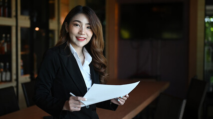 Wall Mural - Portrait beautiful businesswoman in suit holding document and smiling to camera.