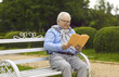 © Studio Romantic - Happy relaxed senior man resting reading an interesting book sitting on a park on a wooden bench. Positive chubby grandfather enjoys free time in retirement. Concept of retirement lifestyle and hobby