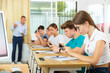 © JackF - Group of modern teenagers sitting with mobile phones on lesson in classroom