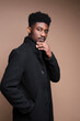 © WellStock - Close-up of African elegant man in black jacket looking at camera isolated on beige background