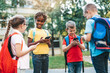 © hedgehog94 - Group of happy elementary school students with smartphones. Primary education, friendship, childhood, and technology concept.