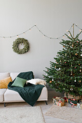 A Christmas fir tree with toys and a sofa with pillows in the interior of the living room in the Scandinavian style