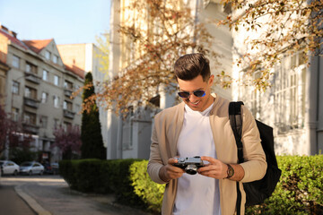 Canvas Print - Happy male tourist with camera on city street