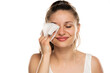 A smiling woman cleans makeup from her face with wet wipe