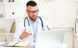 © JenkoAtaman - Focused professional male doctor in white coat giving professional medical consultation to patient online