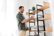 © Syda Productions - home improvement and decoration and people concept - happy smiling man placing seashells in vase to shelf
