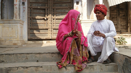 Closeup of an Indian couple in traditional outfits sitting on the stone stairs outdoors.