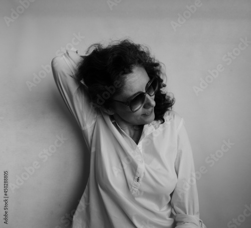 Forty Eight Year Old Woman In Sunglasses Holding Her Hair  Behind Her Head With Her Right Arm