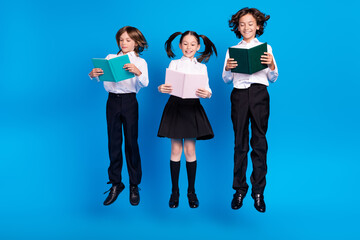 Poster - Photo of smart schoolkids jump read interesting novel wear uniform shoes isolated blue color background