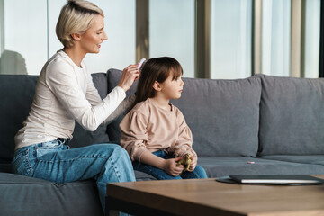 Canvas Print - Happy young mother brushing daughters hair