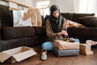 © Drobot Dean - Muslim woman using cellphone while sitting on floor with shopping bags