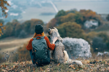 woman hiker with a backpack walks the dog in the mountains in nature