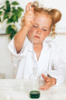 © Tatyana - Little red-haired girl in white uniform conducting chemical experiments in a laboratory.Back to school concept.Young scientists.Natural sciences.Preschool and school education of children.