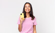 © kues1 - young hispanic woman looking happy and pleasantly surprised and holding a smartphone