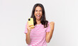 © kues1 - young hispanic woman shouting aggressively with an angry expression and holding a smartphone
