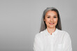 © LIGHTFIELD STUDIOS - joyful middle aged woman in white shirt smiling at camera isolated on grey