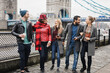 Young friends having fun outdoor at the city with Tower Bridge in London in background - Focus on center girl faces