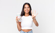 © kues1 - young hispanic woman smiling and looking friendly, showing number four and holding a take away coffee container