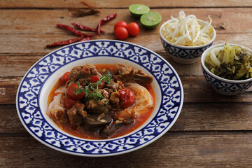 local northern thai food rice noodles with pork in spicy soup in wood background