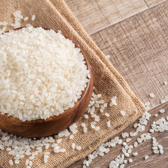 Wall Mural - Raw white rice in a wooden bowl over table.