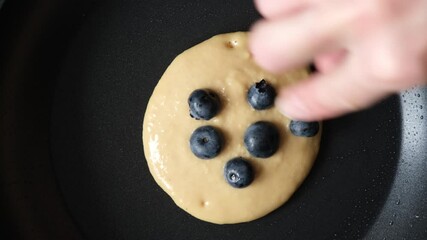 Wall Mural - Frying blueberry pancakes on a pan, top view