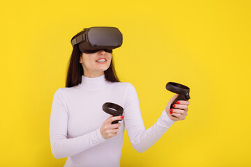 Wall Mural - Girl in glasses of virtual reality with controllers in hands. Woman expresses happiness and surprise. Augmented reality, future technology concept. VR. Yellow background.