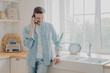 © VK Studio - Handsome busy bearded businessman in casual comfy clothes standing in kitchen with mobile phone