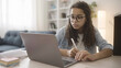 © Synthex - Teenage girl with afro hair doing homework at home, using laptop, distance education